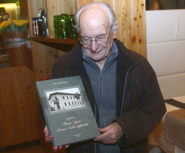 Mario Antolini con il libro per i 100 anni dellAsilo di Tione